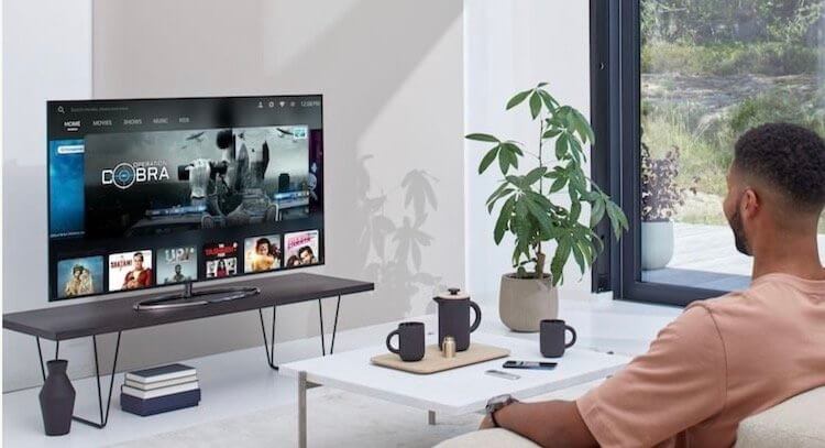 OnePlus покажет дешевый умный телевизор. Как обычно это и бывает в рекламе, очень довольный человек смотрит заставку киносервиса. В этот раз на телевизоре OnePlus. Фото.