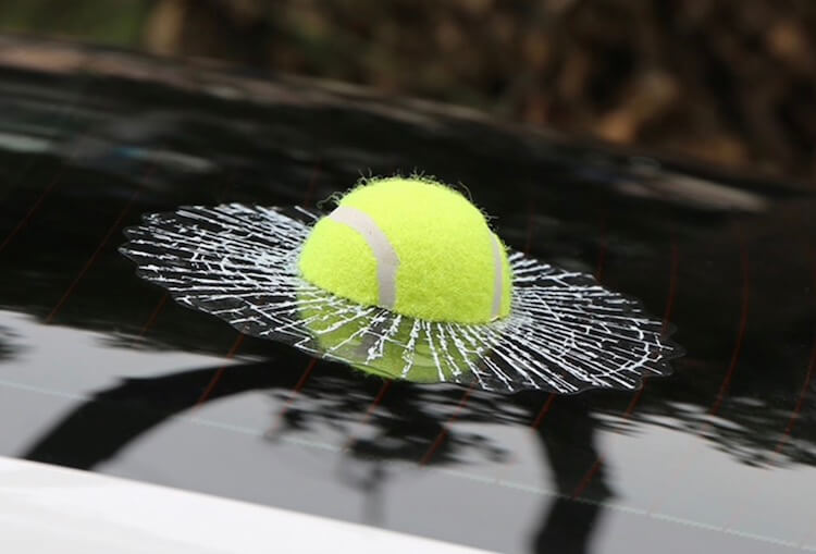 Мячик торчит в стекле машины. Как будто он внутри. Фото.