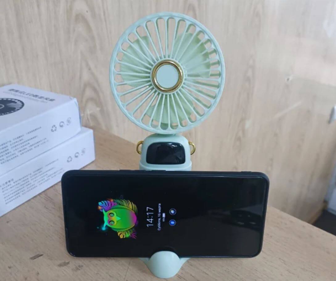 Портативный мини-вентилятор недорого. Компактный вентилятор не только освежит вас, но и поможет удобно разместить смартфон. Фото.