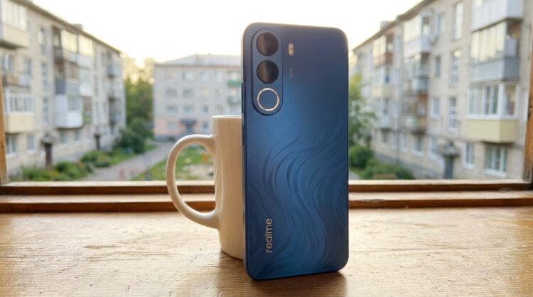 Смартфон Realme на подоконнике рядом с кружкой