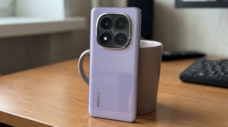 Смартфон Redmi лавандового цвета на столе рядом с кружкой