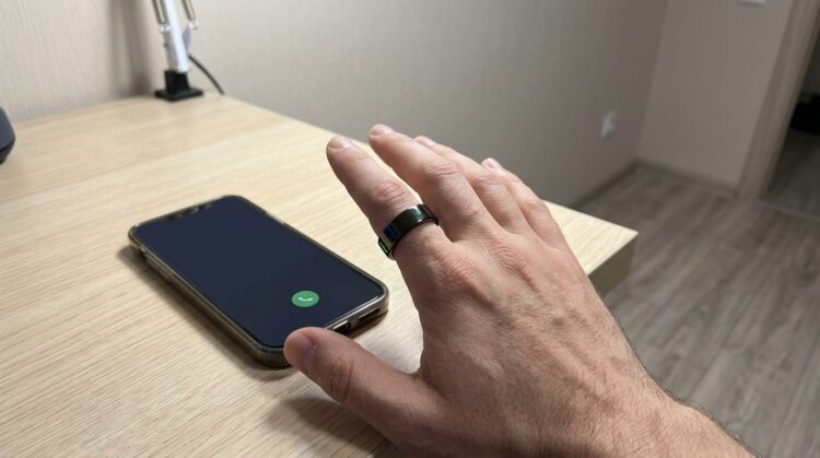 Кольцо WalkerFit на пальце рядом со смартфоном