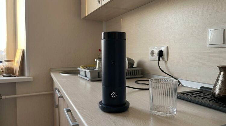 Портативный чайник Xiaomi на подставке показывает 99 °C. Фото.