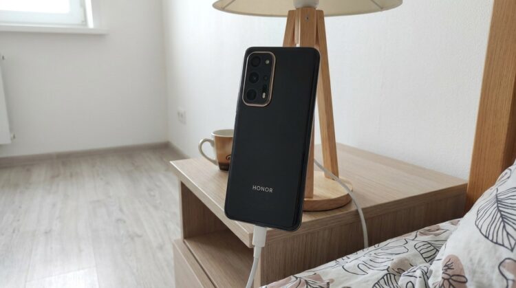 Смартфон Honor на зарядке у прикроватной тумбы